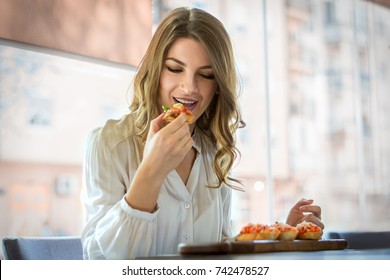 Woman Eating Sandwich Indoors At Cafe