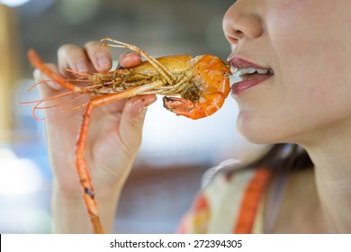 Woman Eating A Shrimp In Restaurant