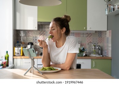 Woman Eating Slowly Pasta With Vegetarian Pesto Sauce, Watching Movie On Smart Phone On Tripod At Home Kitchen. Italian Cuisine, Gluten Free Food. Slow Living. 