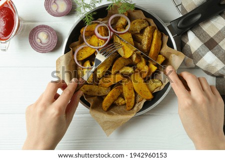 Woman eating tasty baked potato on white wooden table, top view