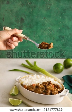 Woman eating tasty beef curry from dish on table
