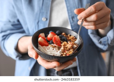 Woman eating tasty granola with berries, yogurt and seeds, closeup - Powered by Shutterstock