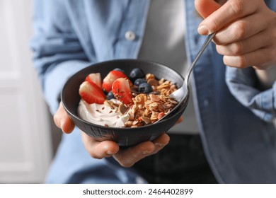 Woman eating tasty granola with berries, yogurt and seeds, closeup - Powered by Shutterstock