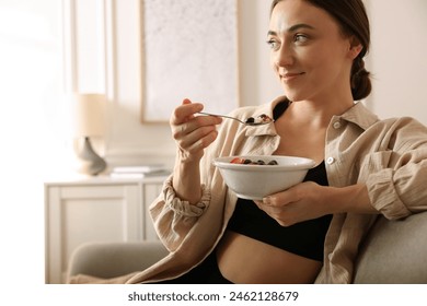 Woman eating tasty granola with fresh berries and yogurt at home - Powered by Shutterstock