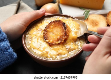 Woman Eating Tasty Homemade French Onion Soup At Black Table, Closeup