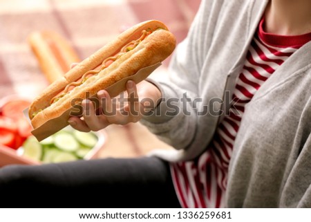 Woman eating tasty hot dog, closeup
