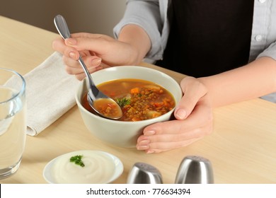 Woman Eating Tasty Lentil Soup At Table