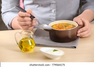 Woman Eating Tasty Lentil Soup At Table