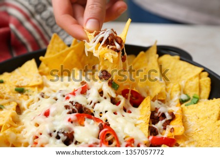 Woman eating tasty nachos, closeup