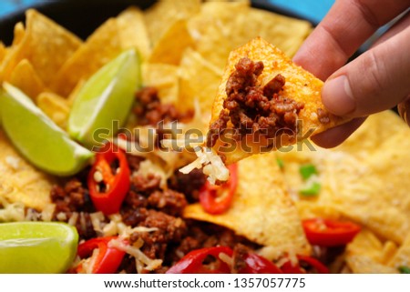 Woman eating tasty nachos with minced meat, closeup