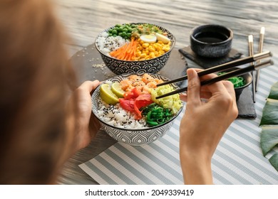 Woman eating tasty rice poke bowl