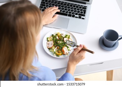 Woman Eating Tasty Salad While Working On Laptop At Home