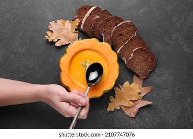 Woman Eating Tasty Soup Served In Pumpkin With Bread On Black Background