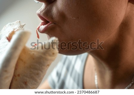 Woman eating tasty taco on grey background. Mexican woman eating tacos al pastor, Mexican food. A woman eats delicious fast food Mexican cuisine quesadilla. Close up