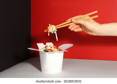 Woman Eating Vegetarian Wok Noodles With Chopsticks From Box On Color Background, Closeup