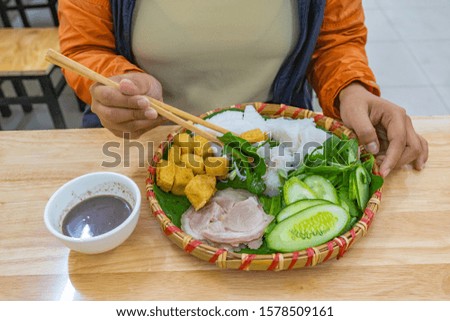 Woman eating Vietnamese fried tofu rice noodles and shrimp paste
