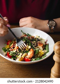 Woman eats healthy food. Hands, fork close up. Salad with spinach, arugula, salmon, almonds, balsamic vinegar, cheese. Homemade food. The concept of delicious and healthy food. Wooden background. Raw