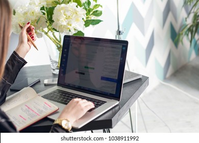 Woman Economist Searching Information Via Net-book Using Textbook During Recreation Time In Cafe. Female Administrator Of Social Networking Groups Working On Laptop Computer And Notes In Notebook 