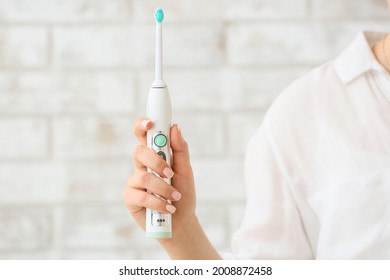 Woman With Electric Toothbrush On Brick Background