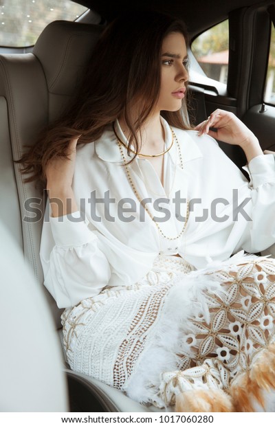 Woman with elegant style and jewelry sitting in\
hear car . Outdoors shot,\
Vertical