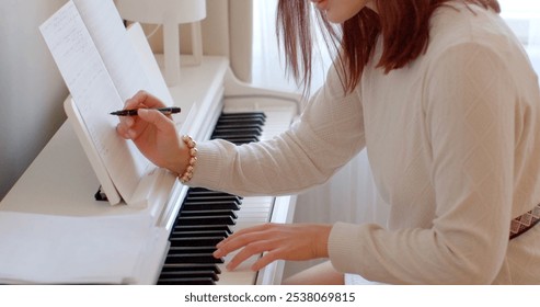 A woman is elegantly playing a beautiful white piano while simultaneously writing on its smooth surface with great concentration - Powered by Shutterstock