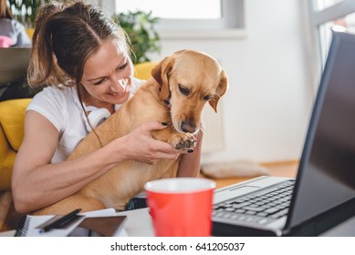 Woman embracing dog sitting on floor smiling and holding his paw