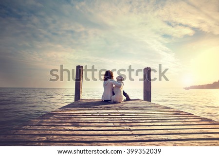 woman embracing sweetly his dog while looking the view