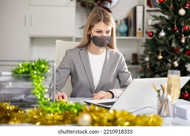 Woman Employee In Face Mask Working In Office With Documents And Laptop During Christmas Time