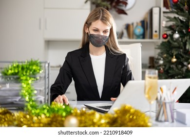 Woman Employee In Face Mask Working In Office With Documents And Laptop During Christmas Time