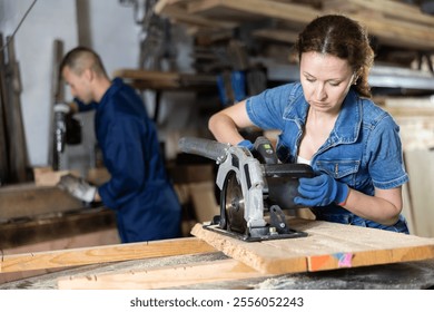 Woman employee performs cutting of wooden board using circular stationary saw. Cutting board into pieces with specified parameters in carpentry workshop - Powered by Shutterstock