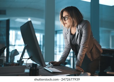 Woman, employee and reading on computer in office on browsing internet, online and research for ideas. Female person, workplace and desk with deadline or overtime, project and standing as hr