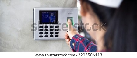 Woman employee scanning fingerprint on the machine to record working time.