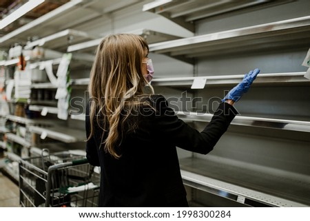 Woman with empty shelves in a supermarket during coronavirus pandemic