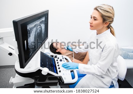 Woman endocrinologist making ultrasonography to a female patient in an ultrasound office. Ultrasound diagnostics of the thyroid gland.