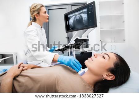 Woman endocrinologist making ultrasonography to a female patient in an ultrasound office. Ultrasound diagnostics of the thyroid gland.