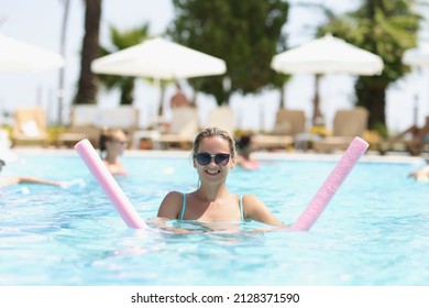 A Woman Is Engaged In Aqua Fitness In An Outdoor Pool, Close-up, Blurry. Aqua Aerobics, Clear Blue Water