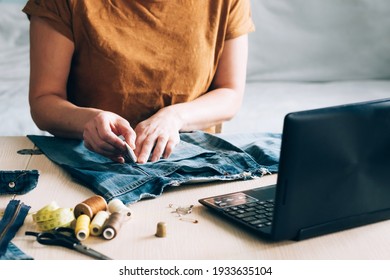 A woman is engaged in online training and looks at sewing lessons on a laptop - Shutterstock ID 1933635104