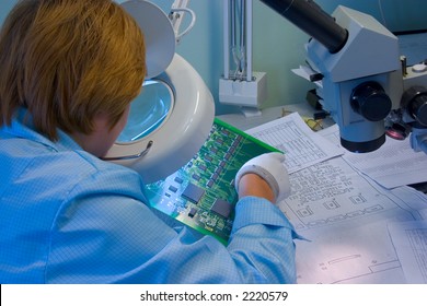 Woman Engeneer Inspecting Computer Mainboard Though Magnifying Glass