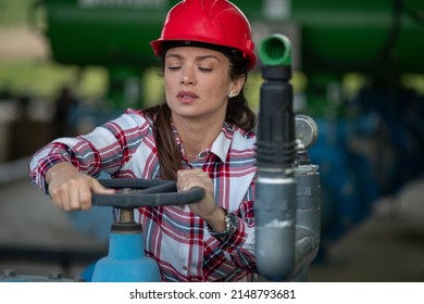 Woman engineer with helmet using her hands to turn the valve on and off in the agricultural industry plant outdoor