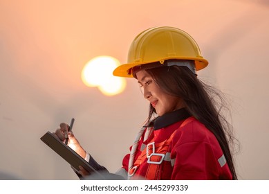 Woman engineer inspection posing check control wind power machine in wind energy factory at silhouette sunset. girl technician professional worker check wind power machine for maintenance turbine - Powered by Shutterstock