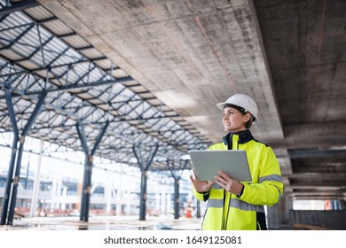 A woman engineer with tablet standing on construction site, working. - Powered by Shutterstock