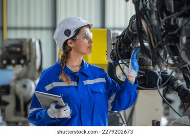 woman engineer in uniform helmet inspection check control heavy machine robot arm construction installation in industrial factory. technician worker check for repair maintenance electronic operation - Powered by Shutterstock