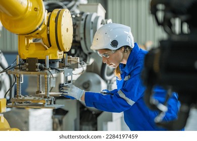 woman engineer in uniform helmet inspection check control heavy machine robot arm construction installation in industrial factory. technician worker check for repair maintenance electronic operation - Powered by Shutterstock