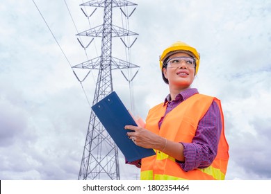 Woman Engineers Construction Worker Checking Layout On Digital Ipad Or Computer. Foreman Working  At Construction Site With Electric Tower Background.