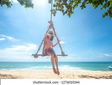 Woman Enjoy Happy The Nature Of The Sea Beach By Sitting On The Wooden Swing Tie Under The Shadow Of The Plam Tree, Long Weekend And Vacation Holidays Spent Slow Life On The Beach - Image