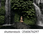 Woman enjoy huge green tropical watefall. Active travel with hiking