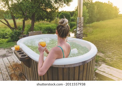 Woman enjoy outside ofuro japanese hot tub in romantic nature environment. Idyllic bathtub in sunset