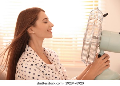 Woman Enjoying Air Flow From Fan Near Window Indoors. Summer Heat