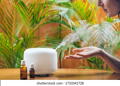 Woman Enjoying Aroma Therapy Steam Scent From Home Essential Oil Diffuser Or Air Humidifier. Ultrasonic Technology, Increasing Air Humidity Indoors For More Comfortable Living Conditions