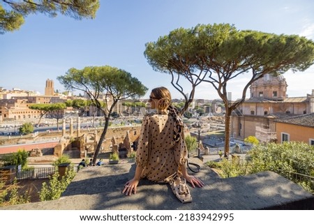 Woman enjoying beautiful view from above on the old centre of Rome. Traveling Italy on a summer day concept. Caucasian woman in dress and shawl in hair visiting Roman forum